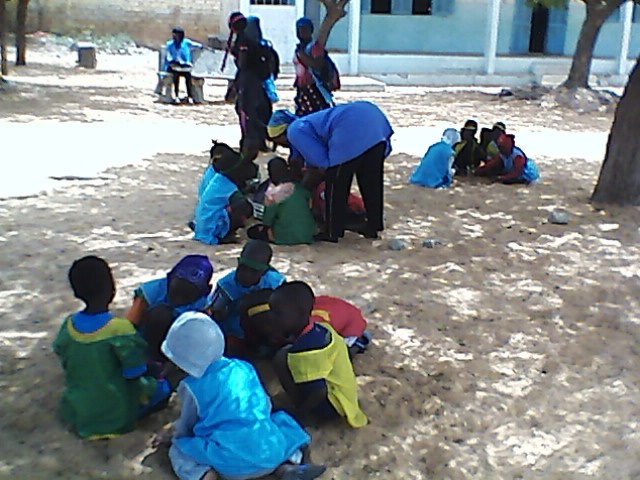 Groupe d'élèves pratiquant le calcul en jouant à un jeu traditionnel du Sénégal dans la cour de récréation